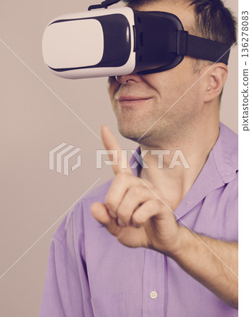 Man wearing virtual reality goggles on grey 136278083