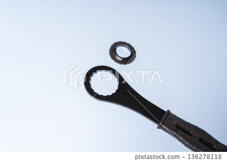 Close-up of a black bicycle disc brake rotor nut near black wrench with black handle with textured grip on a blue background Close-up of a black bicycle disc brake rotor nut near black wrench with black handle with textured grip on a blue background 136278118