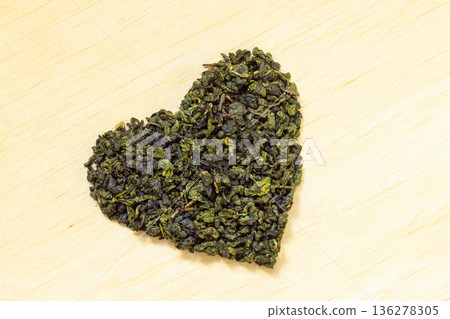 Green tea leaves heart shaped on wooden surface Green tea leaves heart shaped on wooden surface 136278305