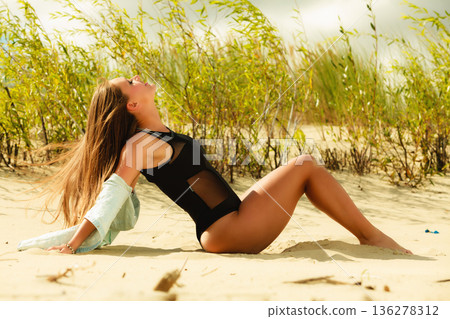 Young woman posing in grassy dune Young woman posing in grassy dune 136278312