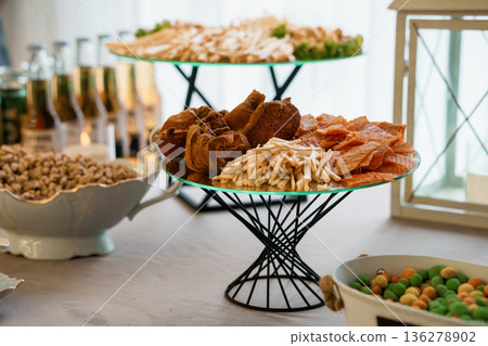 Elegant Tiered Snack Display with Assorted Appetizers, Fresh Mushrooms, and Crispy Treats on Glass Plates Elegant Tiered Snack Display with Assorted Appetizers, Fresh Mushrooms, and Crispy Treats on Glass Plates 136278902