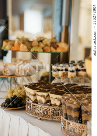 Elegant Dessert Buffet Display with Tiramisu, Fruit, and Pastries on Tiered Gold Stands in Luxurious Event Setting Elegant Dessert Buffet Display with Tiramisu, Fruit, and Pastries on Tiered Gold Stands in Luxurious Event Setting 136278904