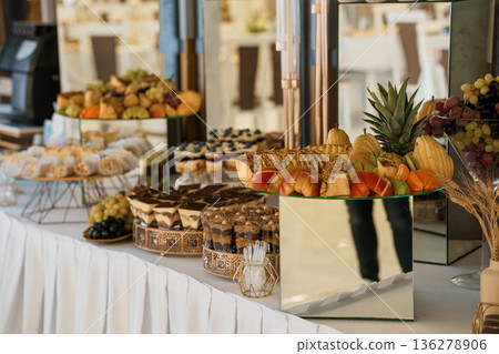 Elegant Buffet Spread with Fresh Fruits, Pastries, and Desserts on Tiered Stands in Modern Event Setting Elegant Buffet Spread with Fresh Fruits, Pastries, and Desserts on Tiered Stands in Modern Event Setting 136278906