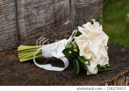 Elegant White Gardenia Bouquet Tied with Ribbon on Rustic Wooden Stump Background 136278913