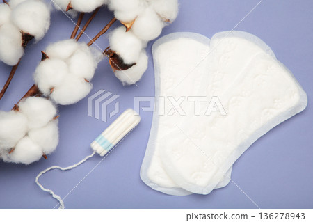 Sanitary pad and cotton flower on purple background. Daily feminine hygiene product. Menstruation and womens health concept. Copy space. Sanitary pad and cotton flower on purple background. Daily feminine hygiene product. Menstruation and womens health concept. Copy space. 136278943