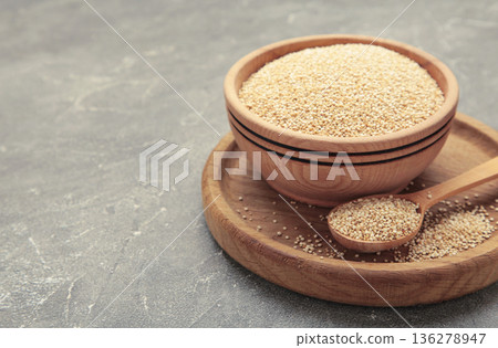 Organic white quinoa seeds in plate and spoon on grey concrete background. 136278947