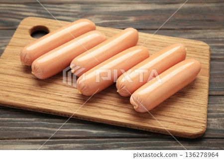 Fresh chicken sausages on cutting board on brown background. Fresh chicken sausages on cutting board on brown background. 136278964