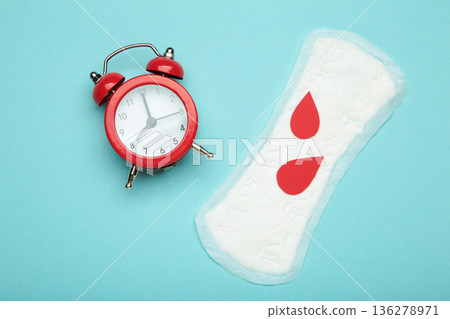 Menstrual pad with clock and red drops on blue background 136278971