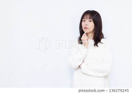 A woman thinking with her arms folded A woman thinking with her arms folded 136279245