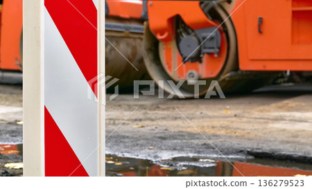 A road safety sign post at a road construction site with an asphalt roller A road safety sign post at a road construction site with an asphalt roller 136279523
