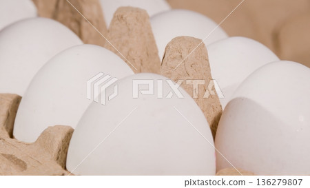 Several white eggs are arranged in a cardboard carton showing a close view of their smooth surfaces and natural colors during daytime Several white eggs are arranged in a cardboard carton showing a close view of their smooth surfaces and natural colors during daytime 136279807