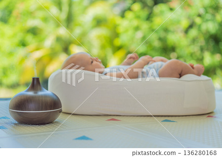 Newborn baby resting in a cozy cocoon beside mother with aroma lamp, calm home atmosphere. Infant relaxation, gentle care, motherhood routine, aromatherapy for babies and family wellbeing concept. Newborn baby resting in a cozy cocoon beside mother with aroma lamp, calm home atmosphere. Infant relaxation, gentle care, motherhood routine, aromatherapy for babies and family wellbeing concept. 136280168