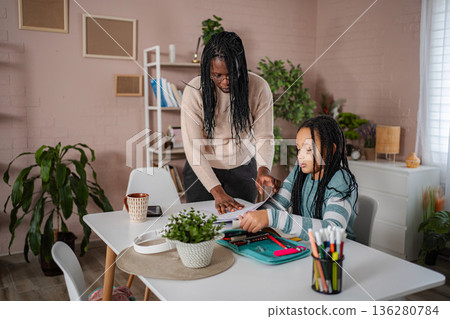 Black mother teaching daughter homeschooling at home Black mother teaching daughter homeschooling at home 136280784