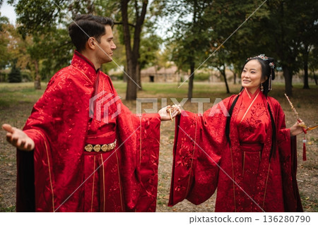 Couple celebrating Chinese wedding ceremony holding hands outdoors Couple celebrating Chinese wedding ceremony holding hands outdoors 136280790