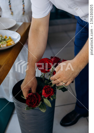Man arranging red roses in vase at home, romantic surprise and flower decor, closeup, copy space Man arranging red roses in vase at home, romantic surprise and flower decor, closeup, copy space 136280805