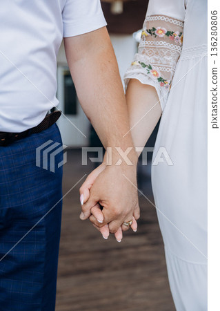Closeup of couple holding hands with wedding rings, white dress and lace sleeve, copy space 136280806