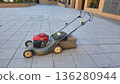Outdoor maintenance with push lawnmower on paved surface in courtyard setting 136280944