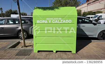 Urban clothing and footwear recycling bin by roadside, promoting sustainability Urban clothing and footwear recycling bin by roadside, promoting sustainability 136280956