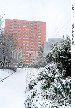 Square Henri Huchard in the 18th district of Paris, France. Winter scene features a large red residential building visible through a heavy snowstorm Square Henri Huchard in the 18th district of Paris, France. Winter scene features a large red residential building visible through a heavy snowstorm 136283998