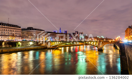 Pont Notre-Dame bridge crosses the Seine river with colorful city light reflections on the water during the evening in Paris, France Pont Notre-Dame bridge crosses the Seine river with colorful city light reflections on the water during the evening in Paris, France 136284002