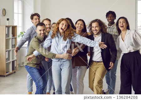 Team of happy diverse business people having fun and hugging in the office all together Team of happy diverse business people having fun and hugging in the office all together 136284208