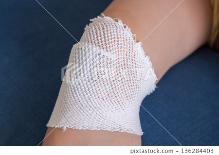 wound dressing bandage on child knee after fall on the ground 136284403