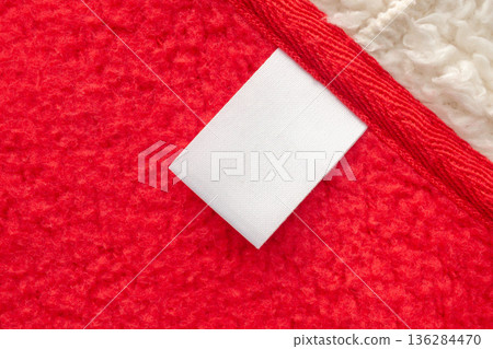 Blank white laundry care clothes label on red shirt fabric texture background Blank white laundry care clothes label on red shirt fabric texture background 136284470