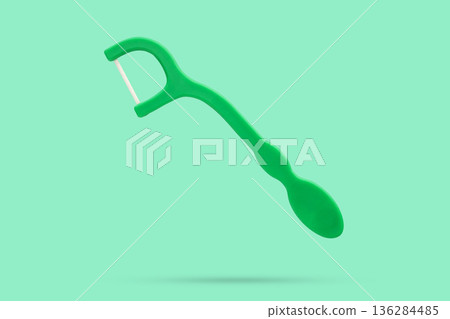 Plastic dental floss pick with handle isolated on green background Plastic dental floss pick with handle isolated on green background 136284485
