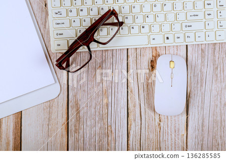 Keyboard, mouse, glasses, notepad sit on office table workspace 136285585