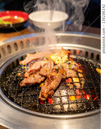 品嚐炭火烤製的頂級和牛。圖中是人們用筷子夾起紋理清晰的牛肉的場景。 136286142