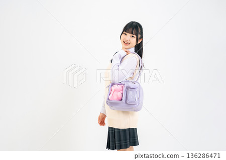 A female student carrying a bag containing a stuffed toy 136286471