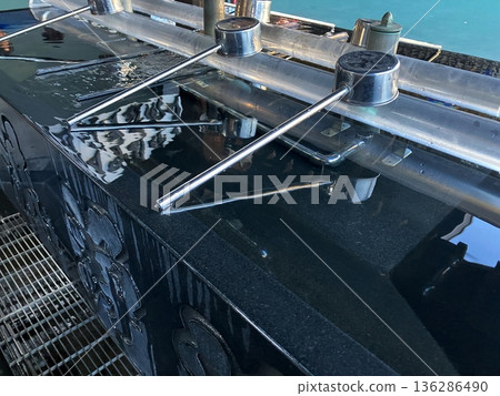 The shrine's chozuya (purification fountain) - clear water reflecting the ladle 136286490