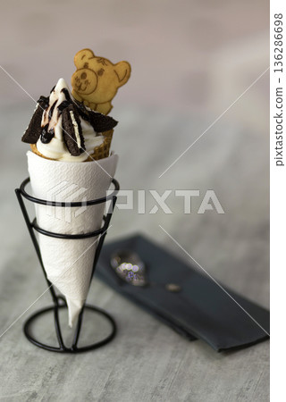 Ice cream cone dessert with cookies creative decoration topping on blurred light copy space background. Ice cream cone dessert with cookies creative decoration topping on blurred light copy space background. 136286698