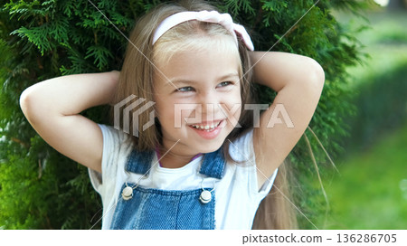 Portrait of pretty child girl standing outdoors in summer park smiling happily. Portrait of pretty child girl standing outdoors in summer park smiling happily. 136286705