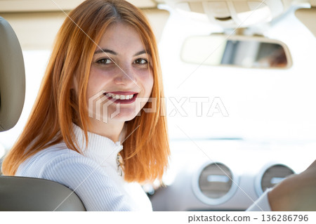 Young redhead woman driver driving a car smiling happily. 136286796