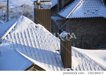 Closeup of house roof top covered with snow in cold winter. Tiled covering of building in wintertime weather 136286817