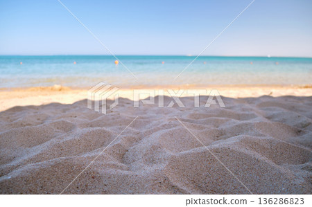 Close up of clean yellow sand surface covering seaside beach with blue sea water on background. Travel and vacations concept Close up of clean yellow sand surface covering seaside beach with blue sea water on background. Travel and vacations concept 136286823