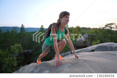 Sportive woman climbing alone on hillside rocky trail. Female hiker overcoming difficult cliff on wilderness path. Active lifestyle concept Sportive woman climbing alone on hillside rocky trail. Female hiker overcoming difficult cliff on wilderness path. Active lifestyle concept 136286838
