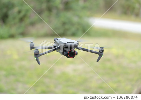 Drone aircraft with blurred fast rotating propellers and video camera flying in air 136286874