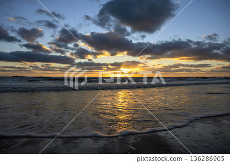 Ocean sunset landscape with soft evening sea water waves crushing on sandy beach 136286905
