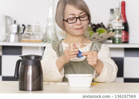 廚房裡，一位老婦人正往杯麵倒熱水。 136287569
