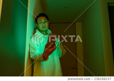 一名男子在走廊上看著他的智慧型手機。 一名男子在走廊上看著他的智慧型手機。 136288257