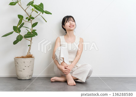 一位微笑的美麗亞洲女子坐在地板上（抬頭，思考，想像，幻想，計劃） 136288580