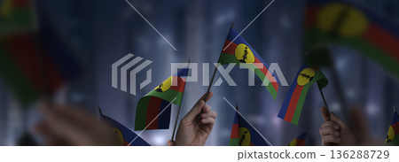 New Caledonia flags in their hands on a blurred urban background New Caledonia flags in their hands on a blurred urban background 136288729