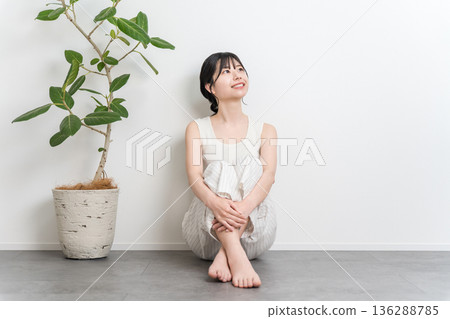 一位微笑的美麗亞洲女子坐在地板上（抬頭，思考，想像，幻想，計劃） 136288785