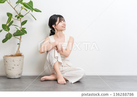 一位微笑的美麗亞洲女子坐在地板上（抬頭，思考，想像，幻想，計劃） 136288786