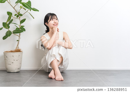 一位微笑的美麗亞洲女子坐在地板上（抬頭，思考，想像，幻想，計劃） 136288951