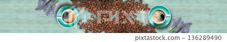 Panoramic top view of two coffee cups surrounded by lavender and plenty of roasted beans on blue wood 136289490