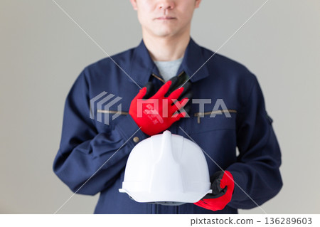A middle-aged male businessman in work clothes holding a helmet and putting his hand on his chest 136289603