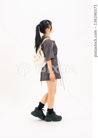Full-body photo of a walking teenage girl from behind 136290371